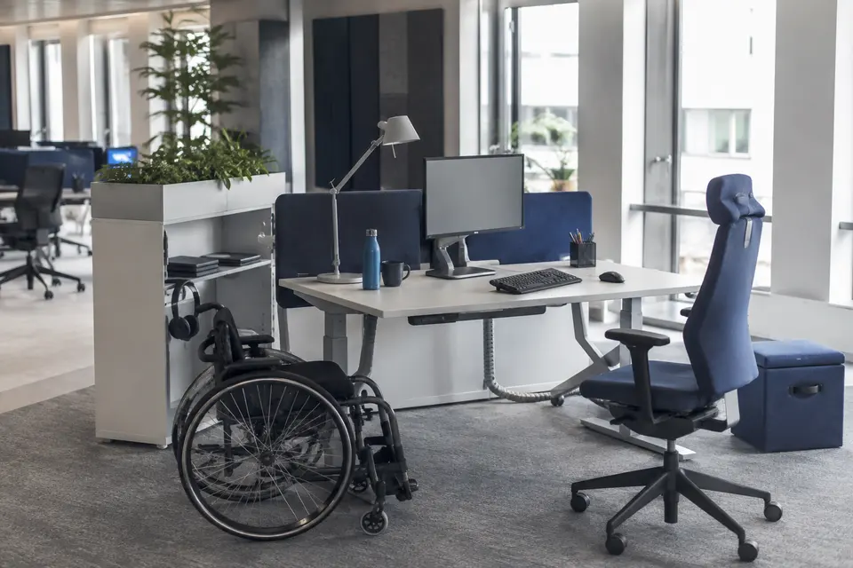 Poste de travail accessible avec bureau réglable, éclairage ajustable et circulation dégagée.